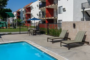 the pool area of an apartment building with chairs and a swimming pool